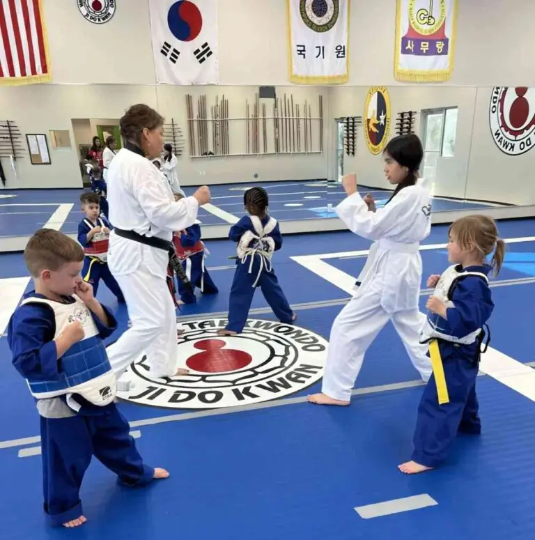 Kids taekwondo class training with instructor in martial arts dojo